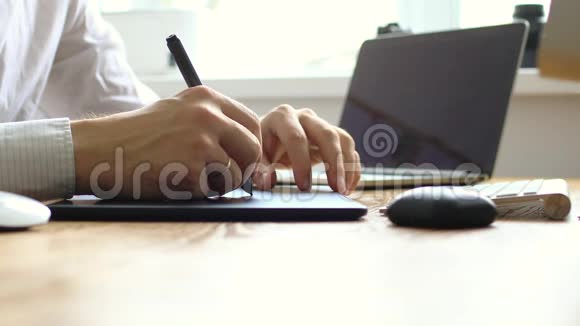 摄影师在笔记本电脑上绘制和润色图像使用数字平板电脑和手写笔家庭工作空间视频的预览图