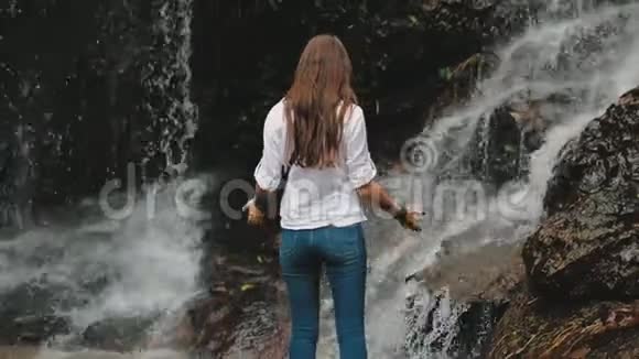 女游客举起双手泼水瀑布视频的预览图