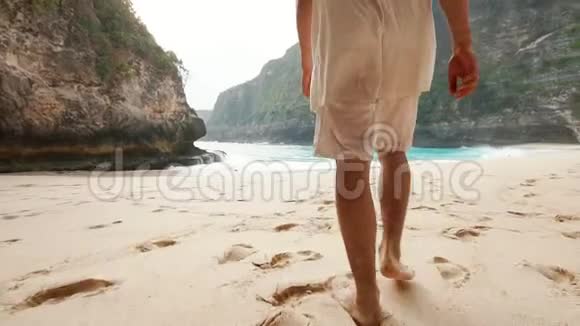 一个人光着脚走在巴厘岛第一区的一个克林金海滩的软沙上视频的预览图