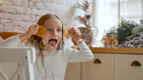微笑的小金发女孩鬼脸和覆盖她的眼睛干橙片在家里阁楼风格和圣诞节视频的预览图