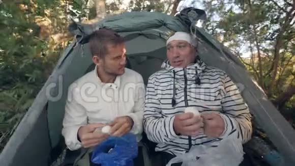 父子俩在露营帐篷里吃煮鸡蛋视频的预览图