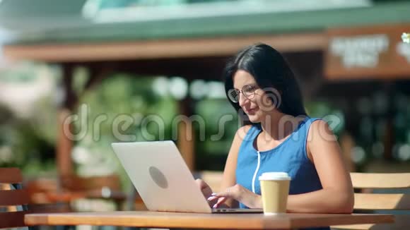 忙碌的自由职业者黑发女孩在户外咖啡馆中弹笔记本电脑工作视频的预览图