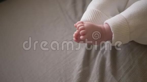 一个孩子光着腿躺在父母棕色的床上视频的预览图