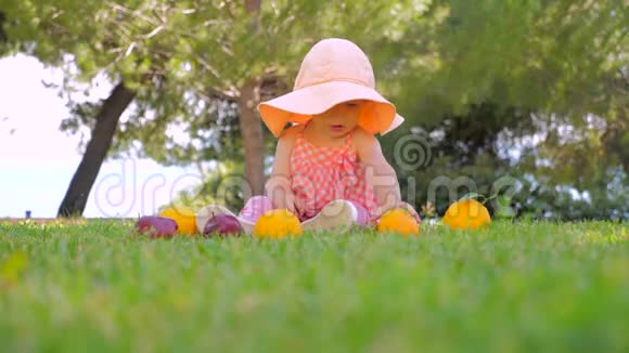 小公主在户外玩水果快乐的童年概念幼儿坐在绿草上等妈妈视频的预览图