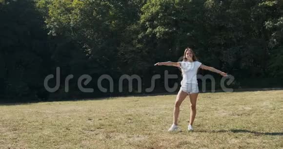 快乐迷人的女性在夏天在草地上锻炼筋斗慢动作视频的预览图