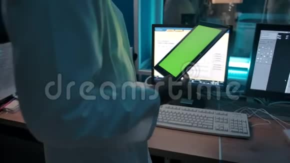 医生带着一块带绿色屏幕的平板电脑从控制室看手术视频的预览图
