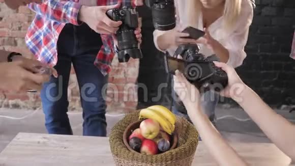 一个大师班的摄影师用照相机和手机把水果放在木桌上的篮子里拍照视频的预览图