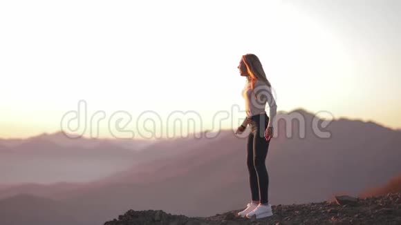 独立的年轻女子在山顶上跳跃在攀登后欣赏风景庆祝成就女孩视频的预览图