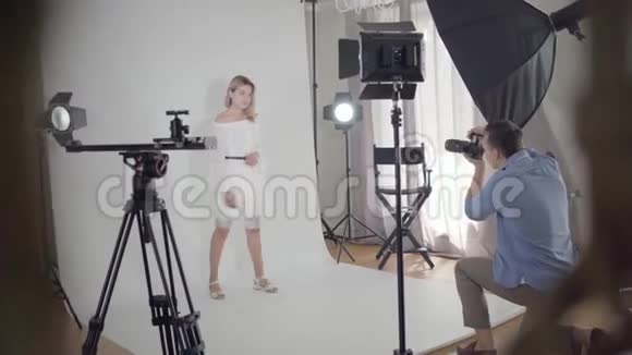 拍摄的后台专业男摄影师为坐在椅子上的可爱优雅女人拍照视频的预览图
