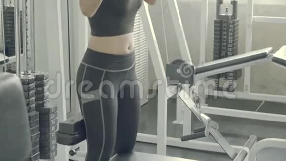 漂亮的年轻亚洲女人在健身房用手在机器上做下拉式锻炼视频的预览图