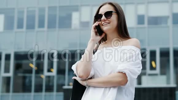 现代年轻女商人通过手机说话背景是商业中心视频的预览图