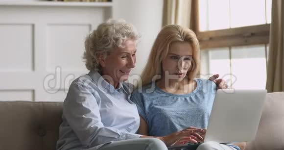 年长的母亲和成年的女儿使用笔记本电脑看屏幕视频的预览图