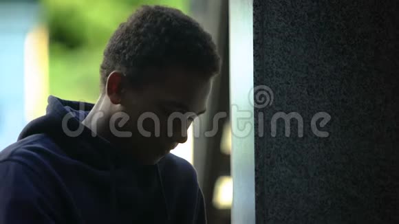 沮丧的非洲裔美国青少年坐在户外靠墙危机视频的预览图