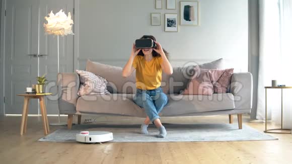 智能家居概念机器人胡佛正在和一个戴着VR眼镜的女人一起打扫公寓视频的预览图