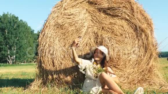 戴草帽戴鲜花的女人在草地上自拍视频的预览图