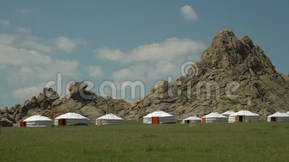 岩石背景下绿色山谷中的蒙古包视频的预览图