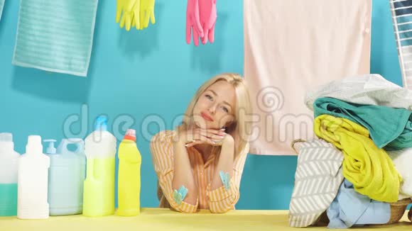 一位美丽的金发女人坐在满是洗涤剂瓶的桌子旁视频的预览图