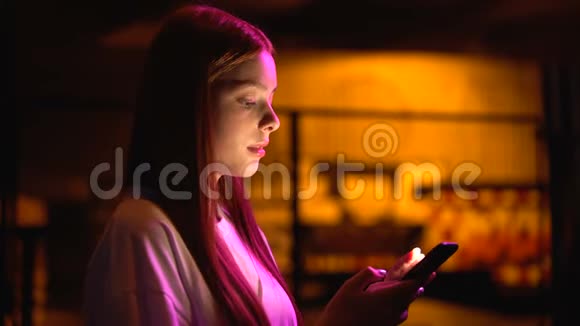 年轻女性在智能手机上滚动网页等待俱乐部附近的朋友视频的预览图