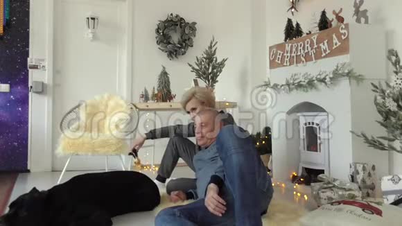 在与他心爱的狗一起拍摄的圣诞照片上壁炉旁是黑色的视频的预览图