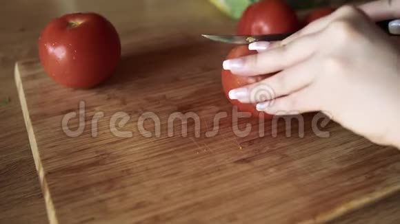 一个女孩的手把西红柿切成方块女孩在家做饭代理板一个女孩切番茄视频的预览图