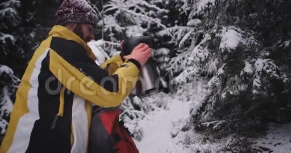 在一个寒冷的冬天里一位激动的游客停在雪林中拿着热水瓶视频的预览图