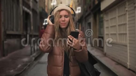 带着耳机听电话音乐唱歌在街上滑稽跳舞的少女画像视频的预览图