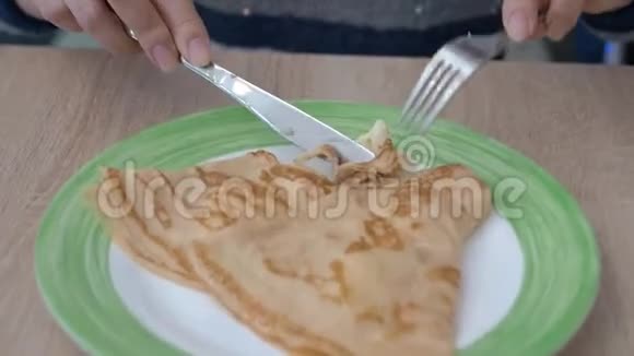 盘子里有两个薄饼女性白种人用刀叉切视频的预览图