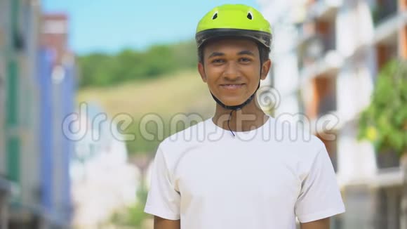 兴奋的美国男青少年戴着防护头盔微笑喜欢骑自行车视频的预览图