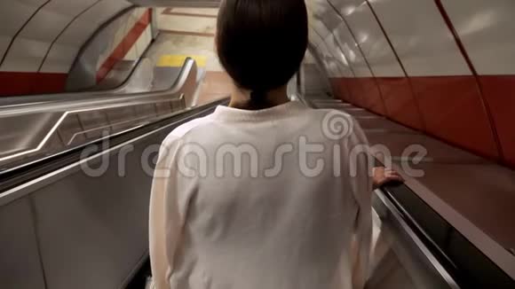 女人开着长长的自动扶梯登上城市地铁视频的预览图