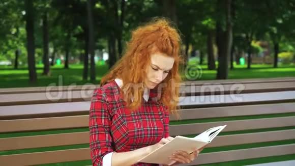 不高兴的红发女孩在公园读惊悚片视频的预览图