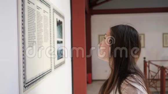 女人站在半张脸上在博物馆里看资料视频的预览图