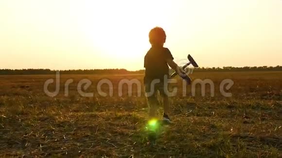 一个小男孩迎着夕阳跑过田野手里拿着一架飞机孩子经历情感视频的预览图