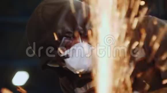 戴呼吸器的人在商店的火花雨后面切割金属部分视频的预览图