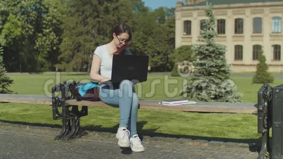 疲惫的学生拿着笔记本电脑在长凳上睡着了视频的预览图