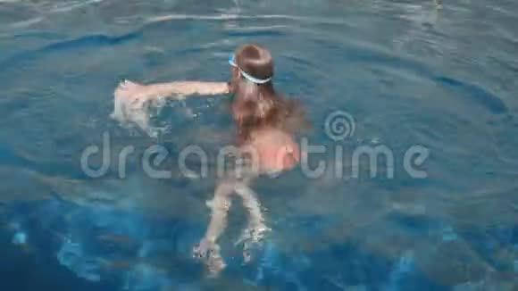 少年女孩在谷歌游泳在浮动游泳池在度假酒店的蓝色游泳池游泳的快乐女孩少女潜水视频的预览图