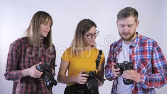 摄影学校年轻摄影师的陪伴他们手里拿着数码相机在演播室里讨论照片视频的预览图
