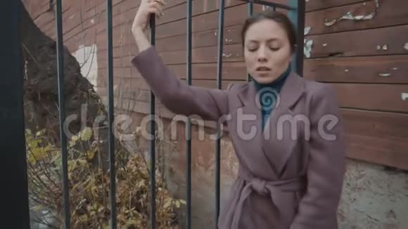 穿外套的女孩把脚放在篱笆上紫胶外套视频的预览图