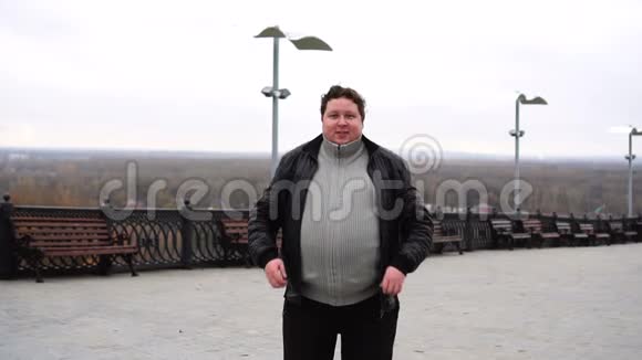 放大肥胖快乐男人的肖像看着相机张开双臂站立视频的预览图