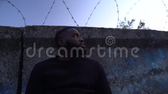 沮丧的美国黑人站在铁丝网附近难民营视频的预览图