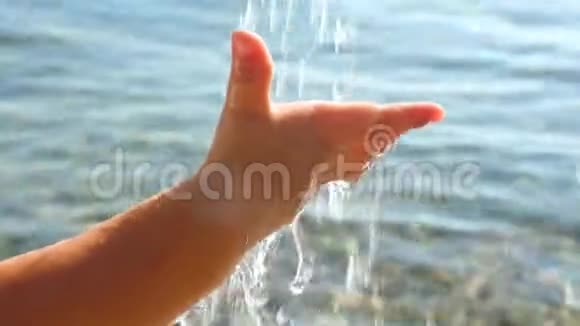 宝贝在海景背景上的手抓水滴幼儿手玩水健康儿童概念视频的预览图