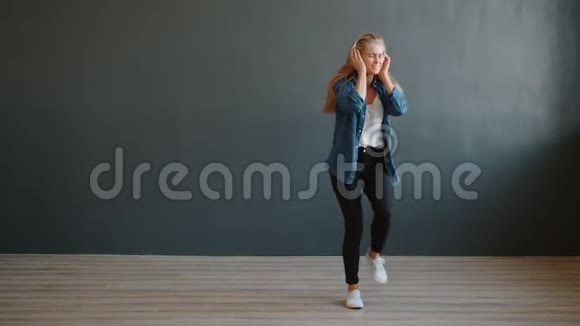 快乐的年轻女士戴着无线耳机在工作室跳舞玩得开心视频的预览图
