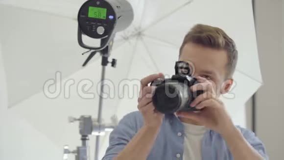 摄影师用照相机站在闪光灯的白色背景上拍照摄影专业摄影环节视频的预览图