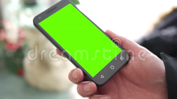 男人拿着带有绿色屏幕的三角针或通用手机视频的预览图