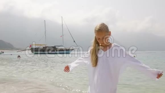 可爱的少女穿着白色长袍在船上欣赏大海的风景站在山上避暑的旅游女孩视频的预览图