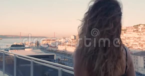 幸福的女人走在阳台上可以看到葡萄牙里斯本的城市年轻女士的后视图与视频的预览图