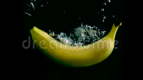 香蕉在水中缓慢运动与阿尔法隔离在黑色背景上近景视频的预览图