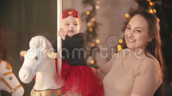 圣诞节概念两个婴儿坐在旋转木马上他们微笑的母亲看着视频的预览图