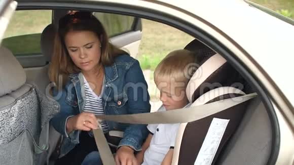 一位母亲把她的小儿子系在汽车座椅上安全带视频的预览图