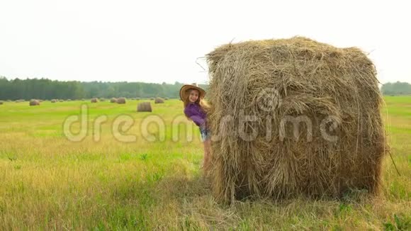 戴着帽子的女牛仔在村里的收割场从干草堆里偷窥戴帽子穿格子衬衫的牛仔女孩视频的预览图