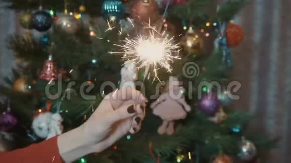 一个女孩在圣诞树的背景下拿着一个闪闪发光的东西视频的预览图